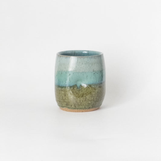 Ceramic cup with two-tone in blue and green glaze on a white background